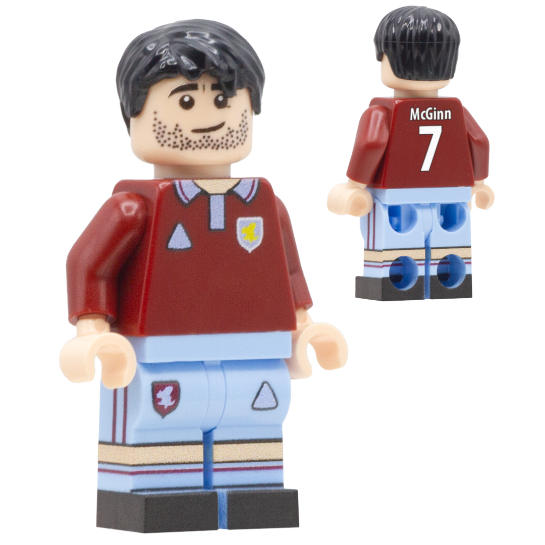 A toy minifigure of Aston Villa FC footballer John McGinn. The figure wears a dark red soccer jersey with a light blue collar, a small yellow star crest, and light blue shorts with dark red stripes.
