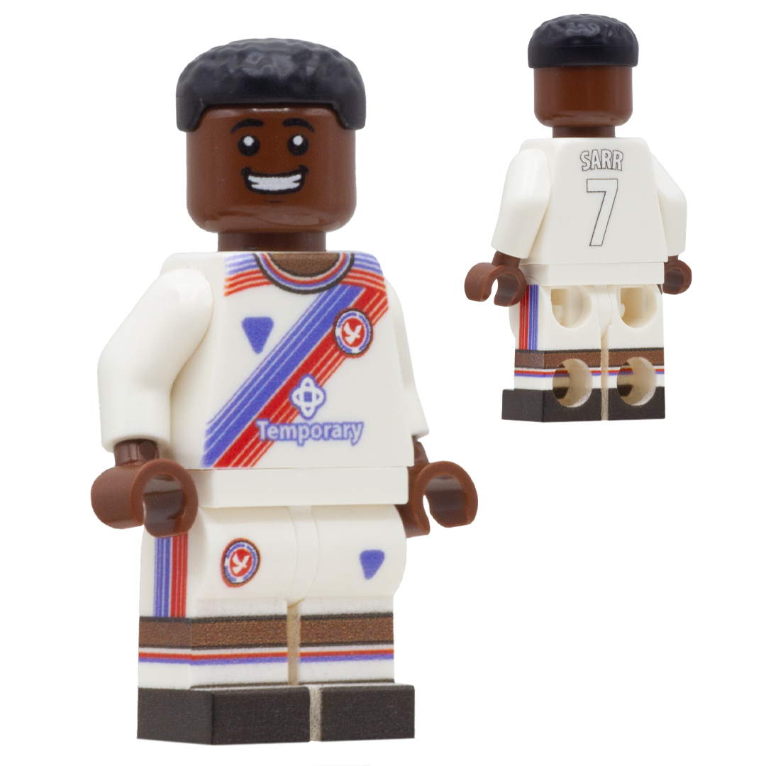 A custom minifigure of a Crystal Palace FC footballer, Ismaila Sarr. The figure has dark brown skin, black hair, and is wearing a white jersey and shorts with red, blue, and brown accents, including the name 'SARR' and number '7' on the back.