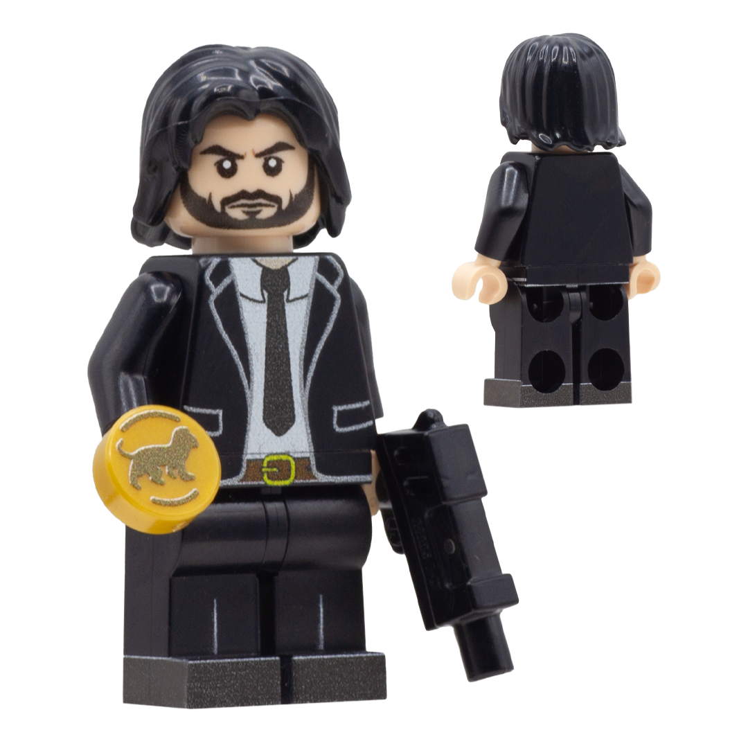 A black minifigure with long dark hair, a beard, and a black suit, shown from the front and back on a plain white background. The front figure holds a gold coin with a lion emblem and a black gun. John Wick Custom LEGO Minifigure.
