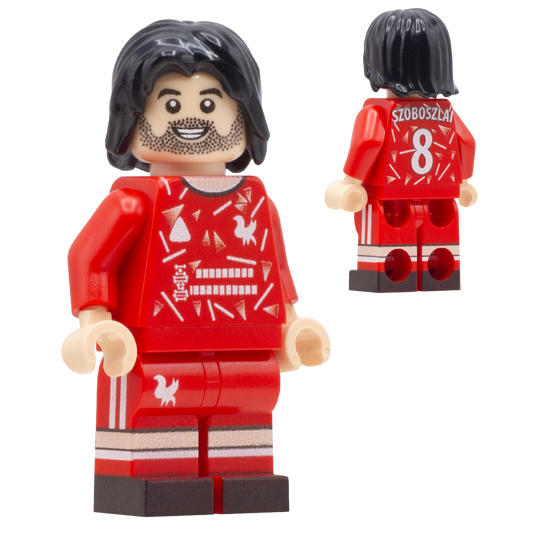 A red LEGO-style soccer minifigure of Liverpool FC footballer, Dominik Szoboszlai. The front view shows a smiling face, black hair, beard, red jersey with white graphic patterns, matching red shorts.