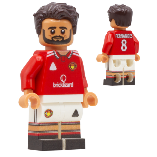 A LEGO-style football minifigure of Manchester United footballer Bruno Fernandes. The figure wears a red jersey with white shorts and striped accents, and the back shows the name FERNANDES and number 8.