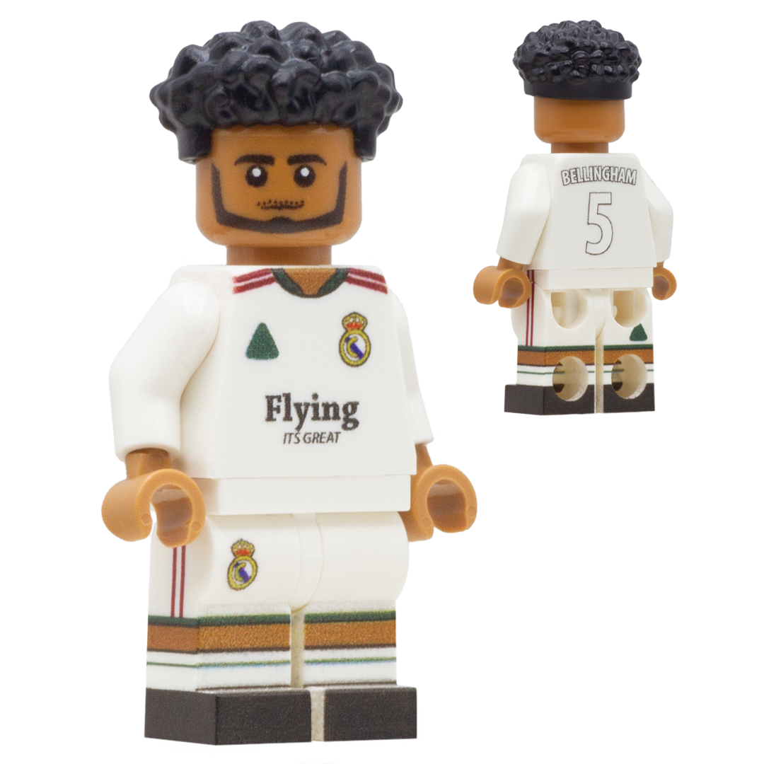 A soccer minifigure of Real Madrid footballer, Jude Bellingham. The figure has black curly hair, brown skin, and wears a white Real Madrid jersey with green and red accents, plus matching white shorts.