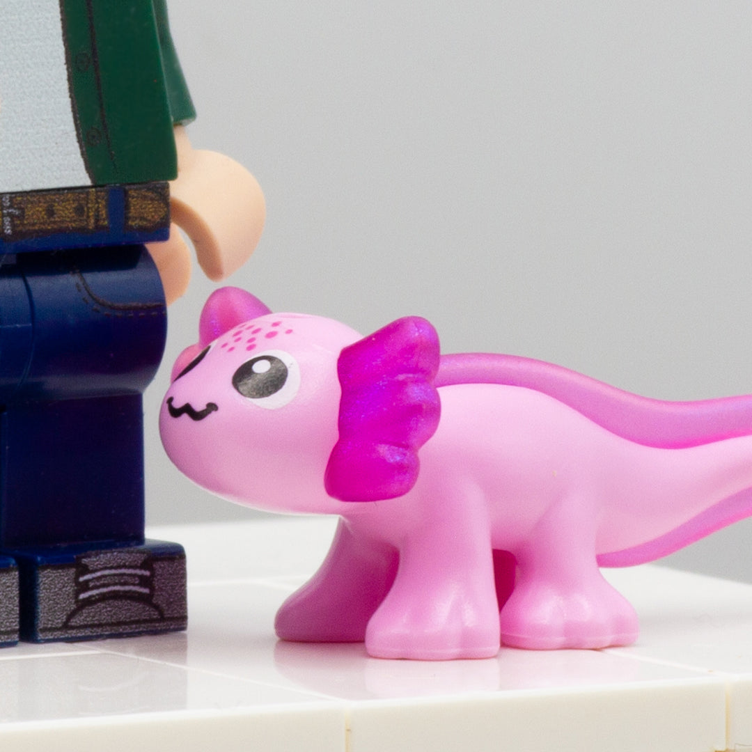 Cute pink LEGO axolotl accessory with big eyes and smile, standing next to LEGO minifigure