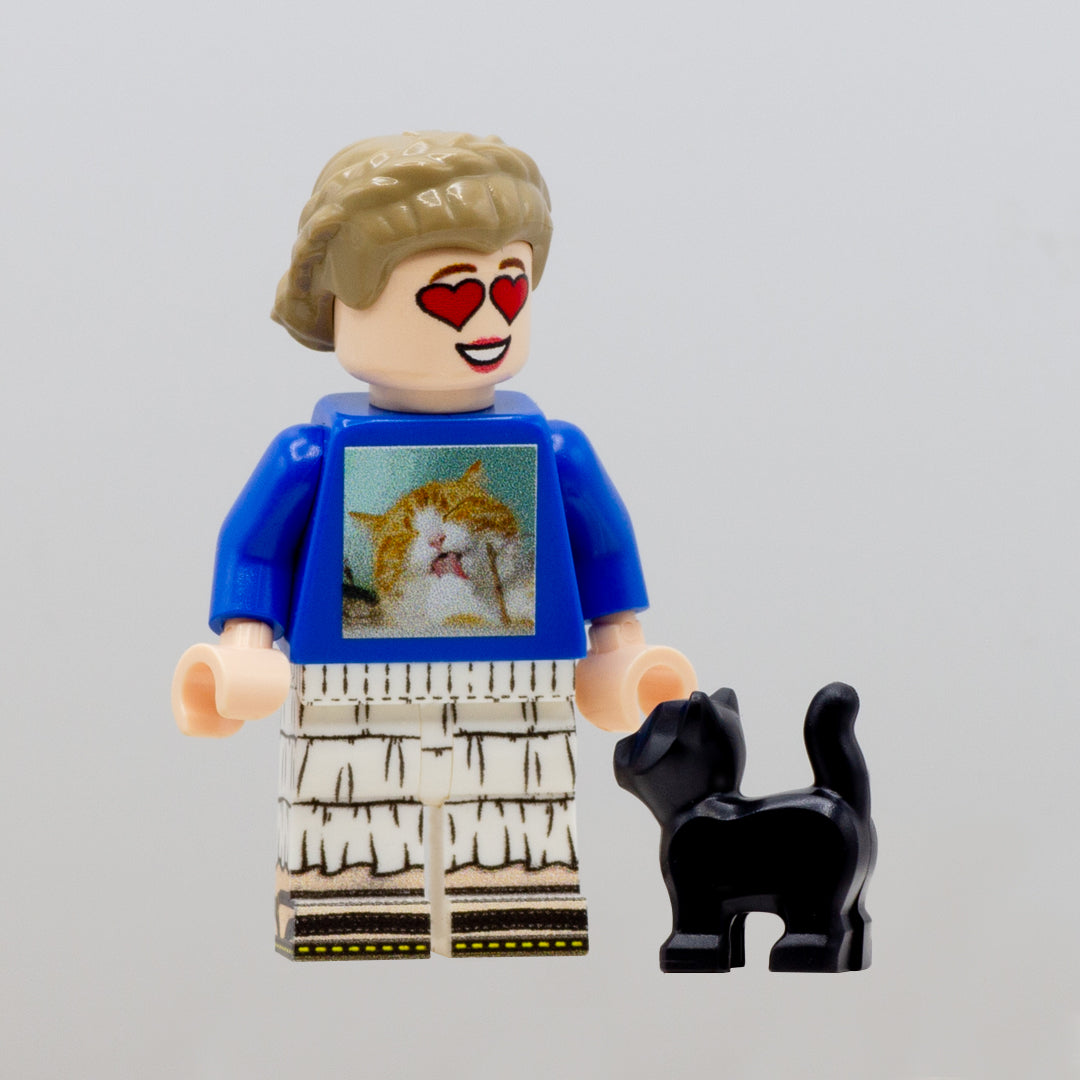 A small black LEGO  kitten standing next to a minifigure.