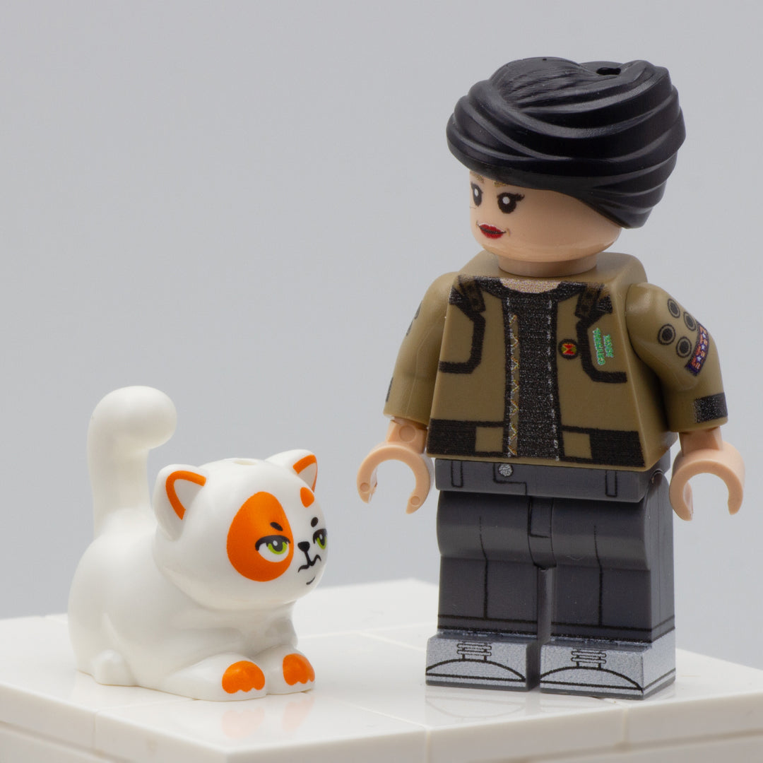 Minifigure standing next to a chubby white LEGO cat with ginger patches and socks with a grumpy face