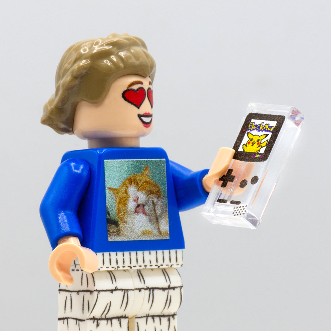Custom LEGO minifigure holding a translucent Nintendo Game Boy console printed on a LEGO tile