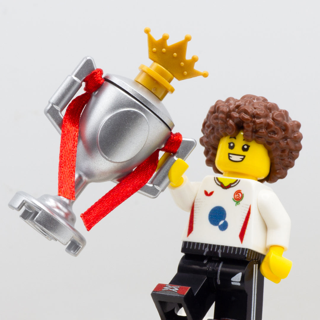 LEGO minifigure cheering and holing a large silver LEGO trophy