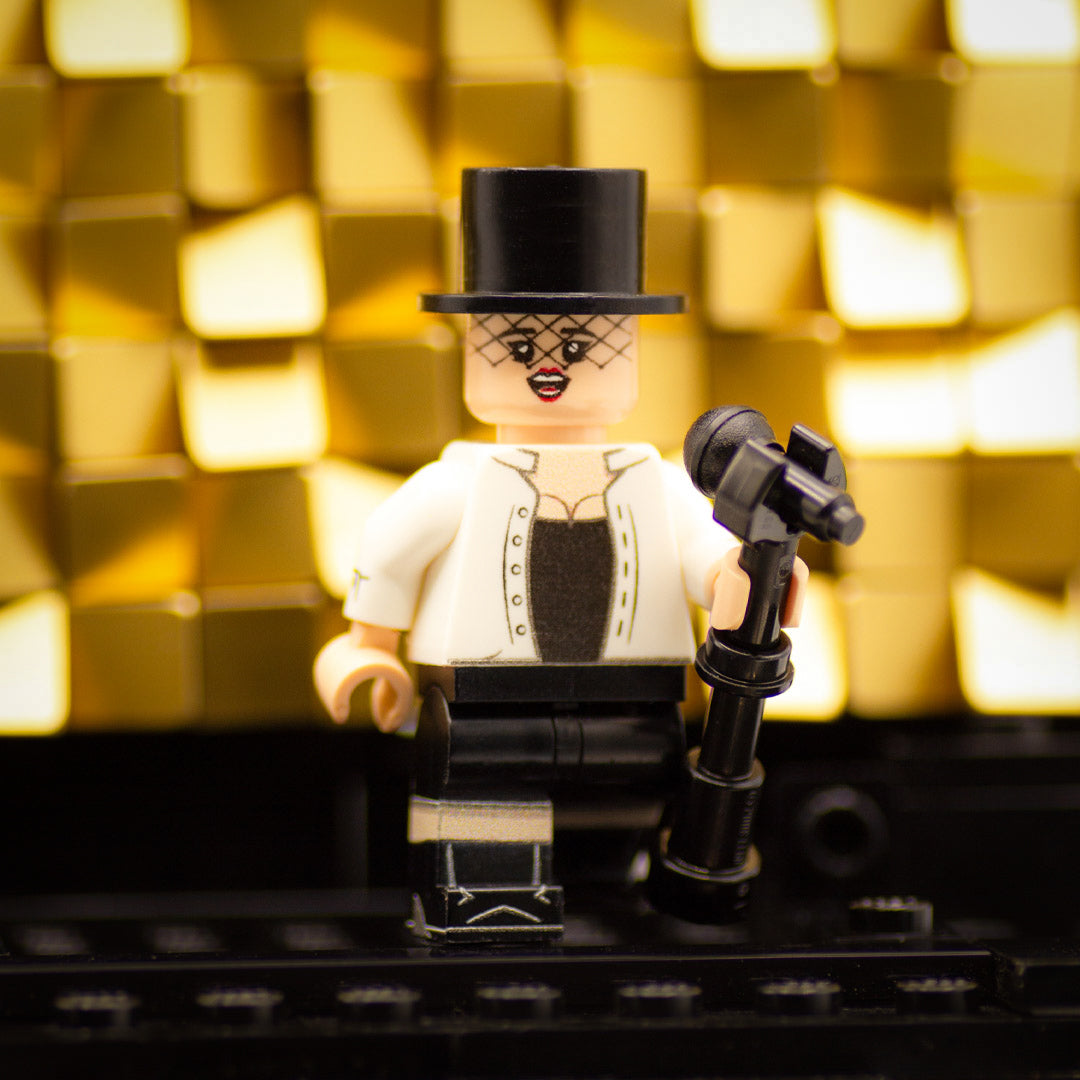 Custom printed LEGO Minifigure inspired by Shania Twain standing on a stage and wearing white shirt and top hat.