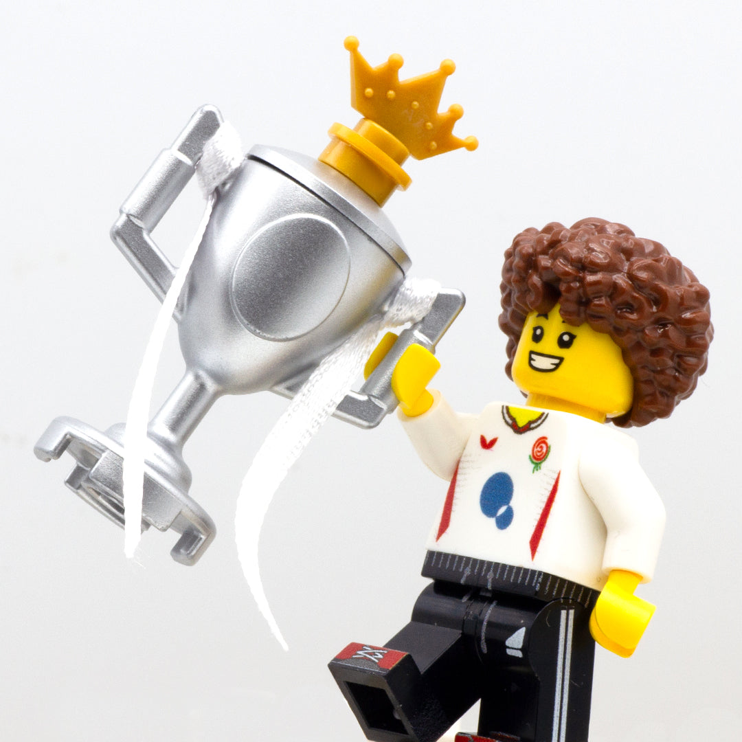 LEGO minifigure cheering and holing a large silver LEGO trophy